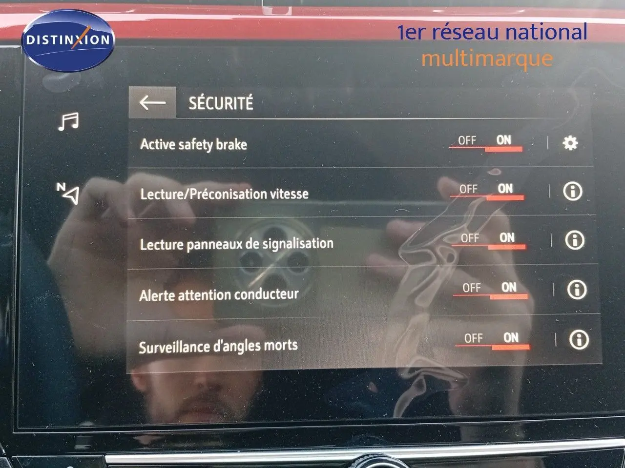 Écran tactile du système de sécurité de l'Opel Corsa 2023 rouge Kardio métal avec toit noir, affichant les options activées.