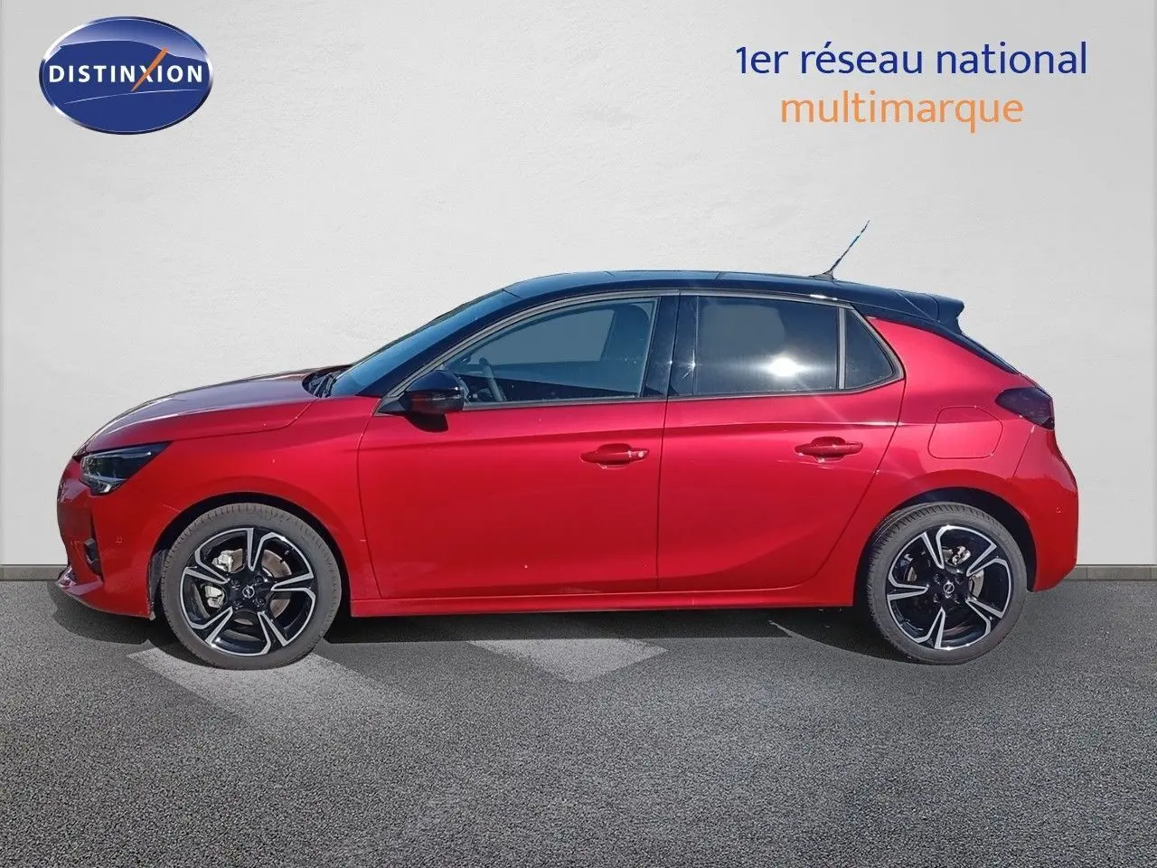 Profil gauche d'une Opel Corsa 2023 rouge Kardio métallisé avec toit noir et jantes alliage noires.