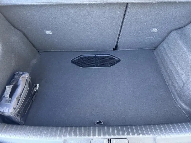 Vue plongeante sur le coffre spacieux et propre du DS3 1.2 Hybride bleu, avec un sac noir rangé sur le côté gauche.