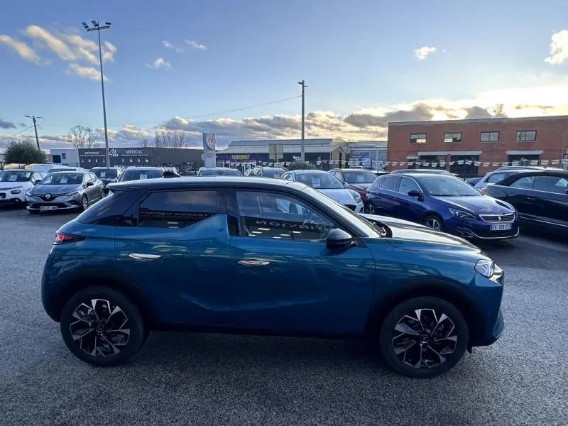 Vue de profil côté gauche d'une DS3 1.2 Hybride bleu avec toit noir et jantes alu au design moderne.