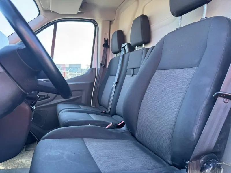 Vue intérieure côté conducteur du Ford Transit Fourgon 2020 montrant la banquette 3 places en tissu gris foncé et noir.