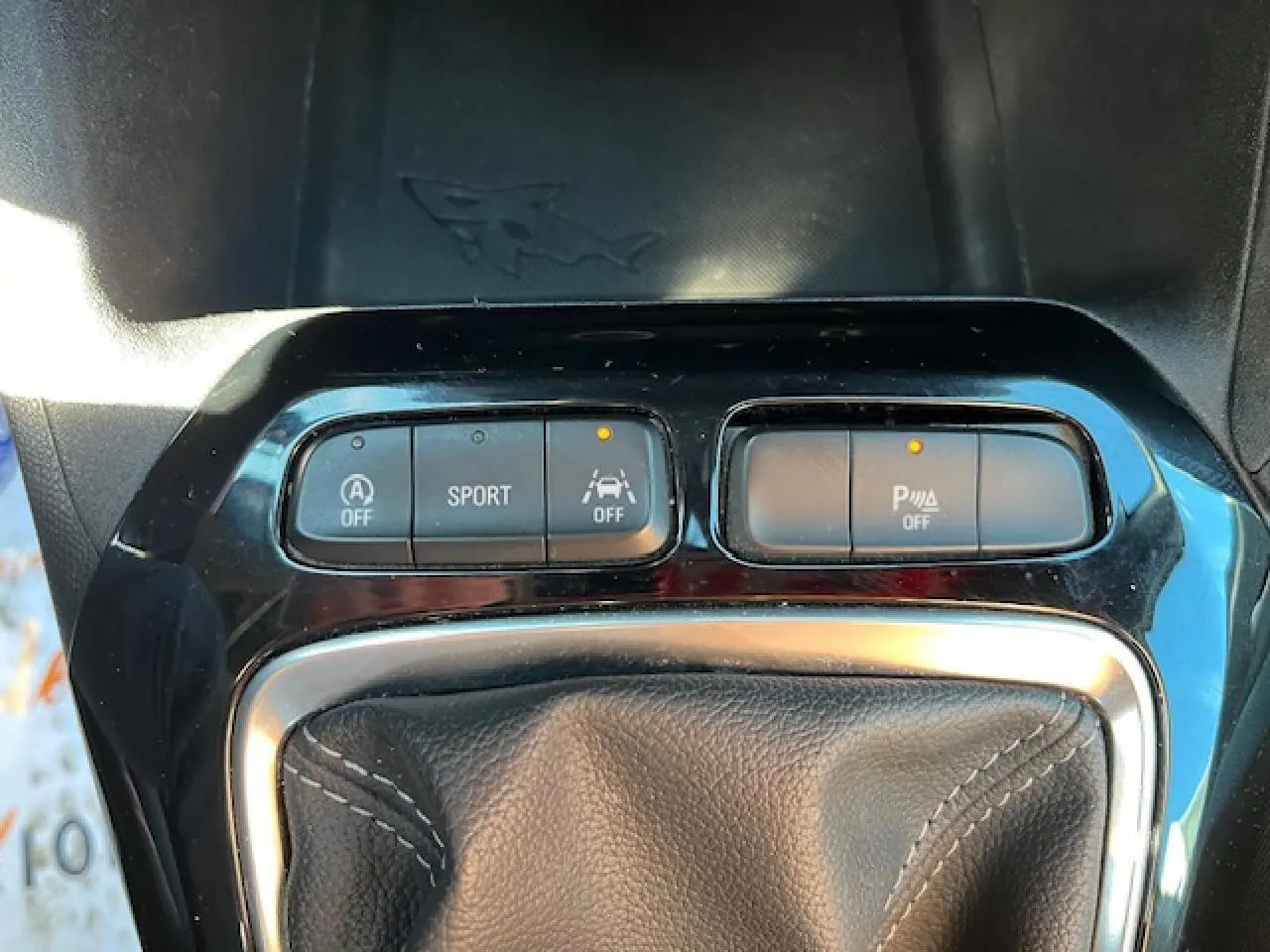 Gros plan sur la console centrale de l'Opel Corsa 2021, boutons de mode sport et aide au stationnement activés.
