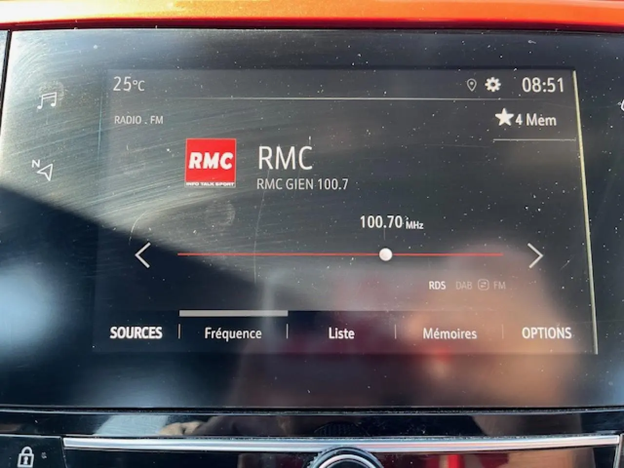 Écran tactile de la radio FM affichant la station RMC 100.7 MHz dans l'habitacle d'une Opel Corsa gris/noir.