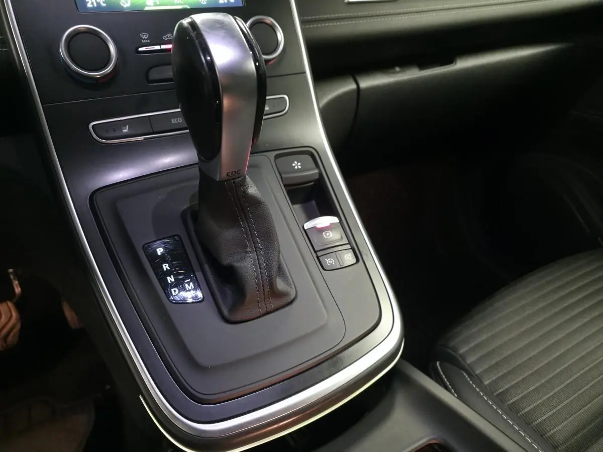 Gros plan sur la console centrale avec levier de vitesse automatique cuir et sièges noirs du Renault Scenic Grand Blanc.
