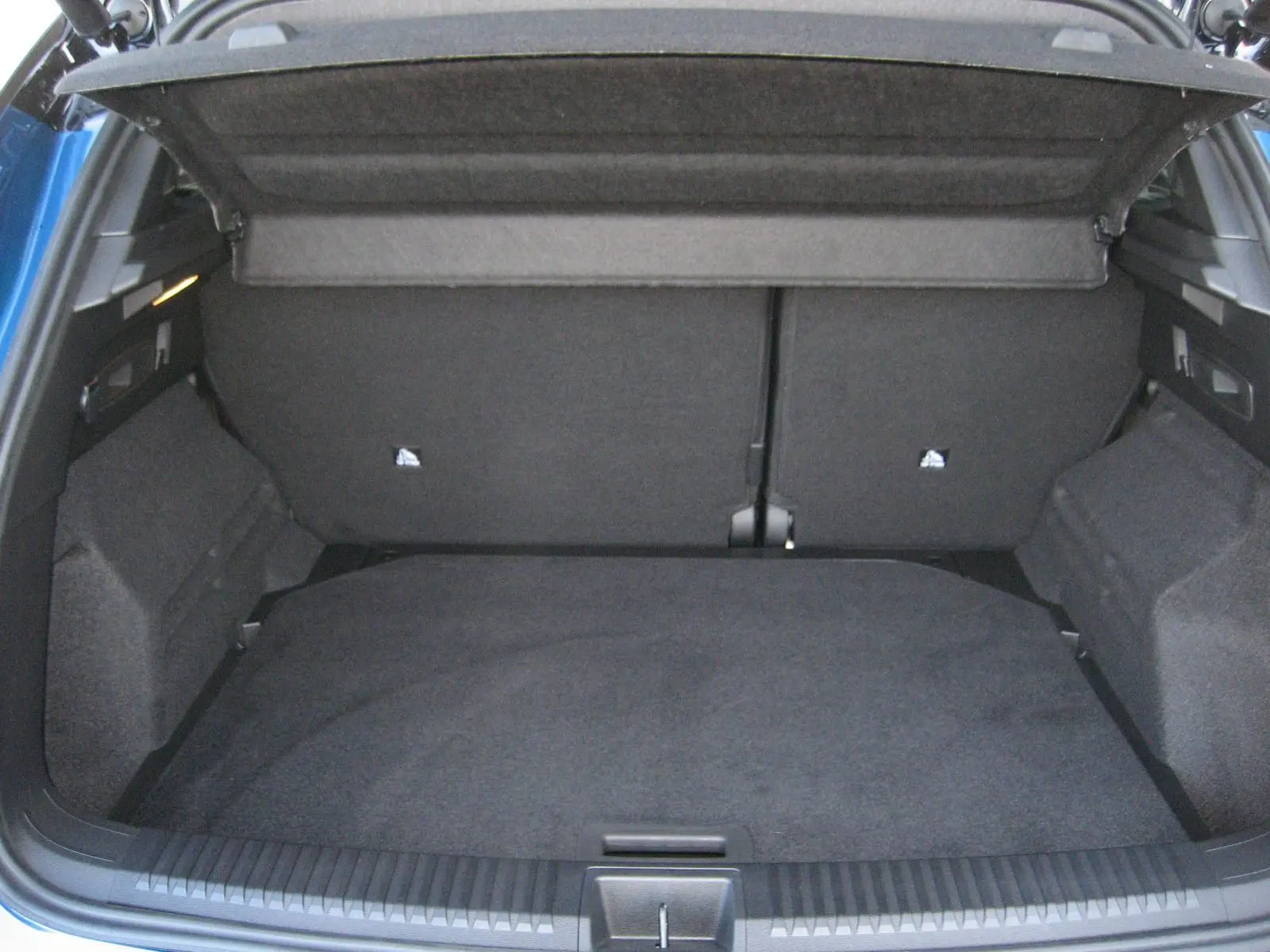 Coffre ouvert vu de l'arrière d'un Renault Austral bleu outremer avec intérieur de coffre noir et cache-bagages déployé.