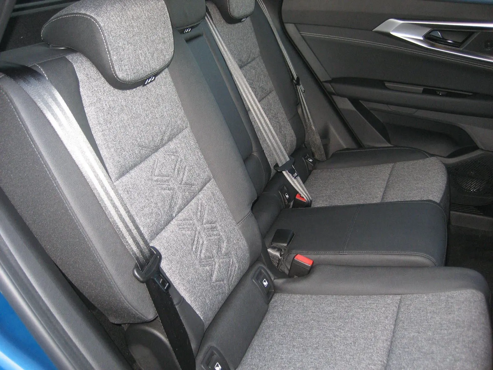 Vue intérieure sur la banquette arrière grise et noire du Renault Austral 2025, avec accoudoir central et ceintures visibles.