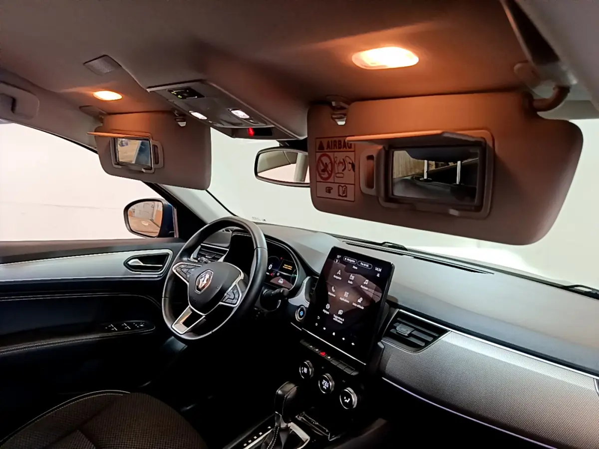 Intérieur noir du Renault Arkana bleu, vue côté conducteur, tableau de bord avec écran tactile vertical et volant multifonctions.