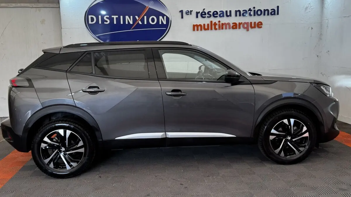 Profil droit d'un Peugeot 2008 gris foncé 2022 avec jantes alliage noires et toit noir contrasté.
