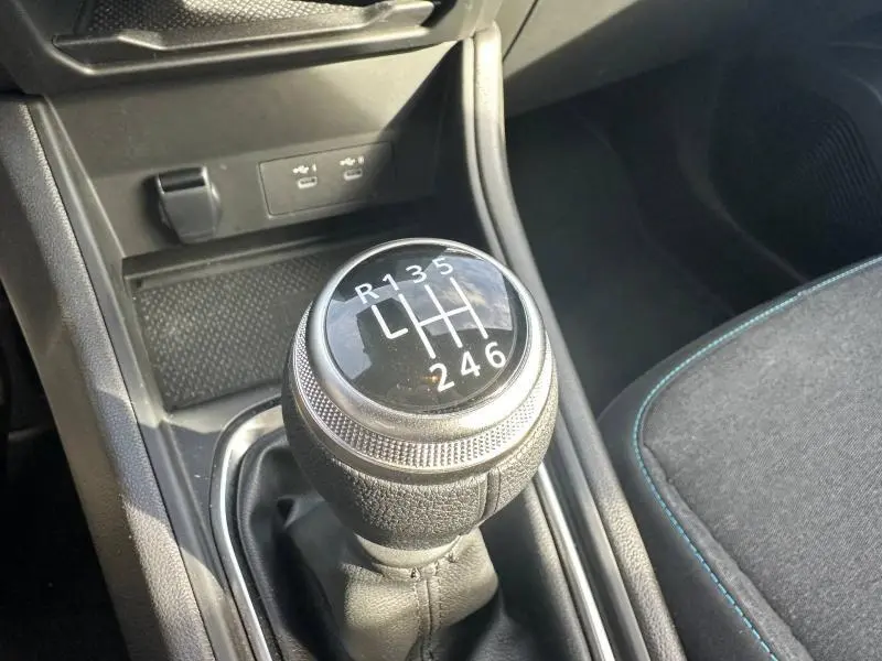 Gros plan sur le levier de vitesse manuel noir du Renault Captur 2025, avec coutures bleues visibles sur le siège côté droit.