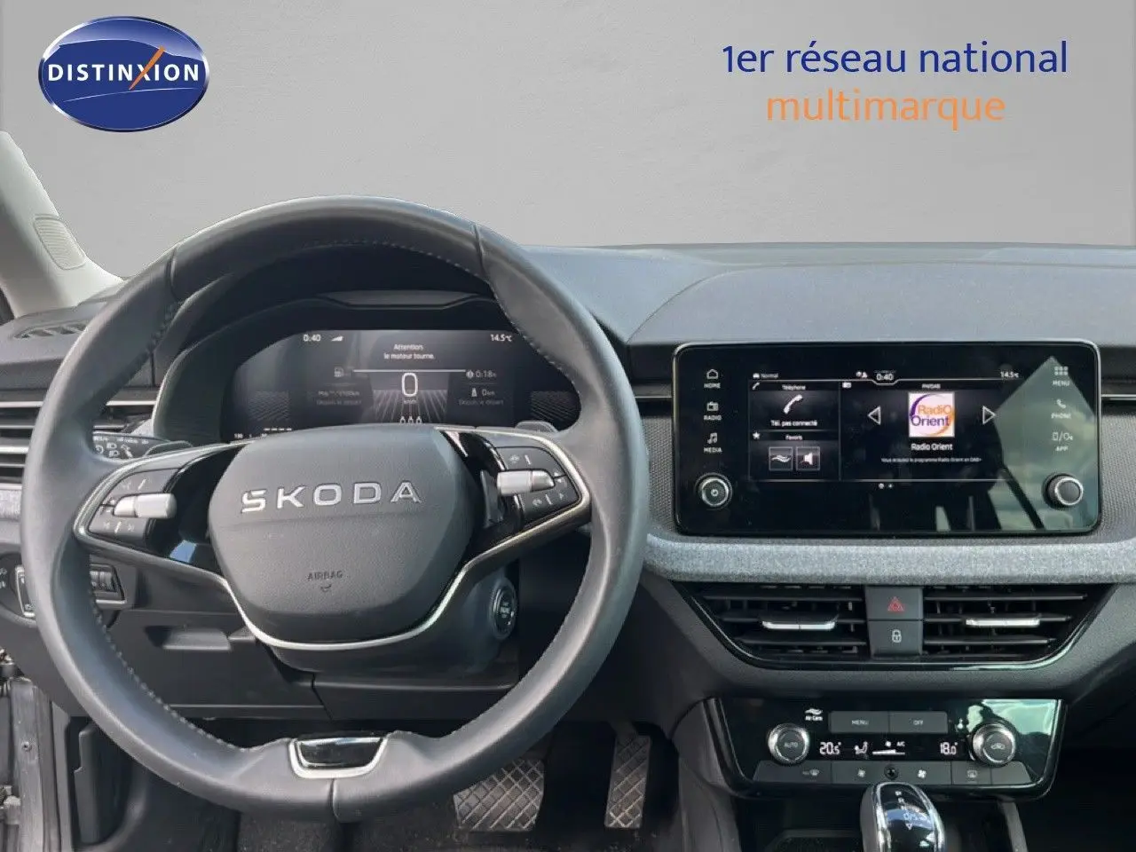 Vue intérieure centrée sur le volant noir et l’écran tactile du tableau de bord d’une Skoda Scala gris magnétique.