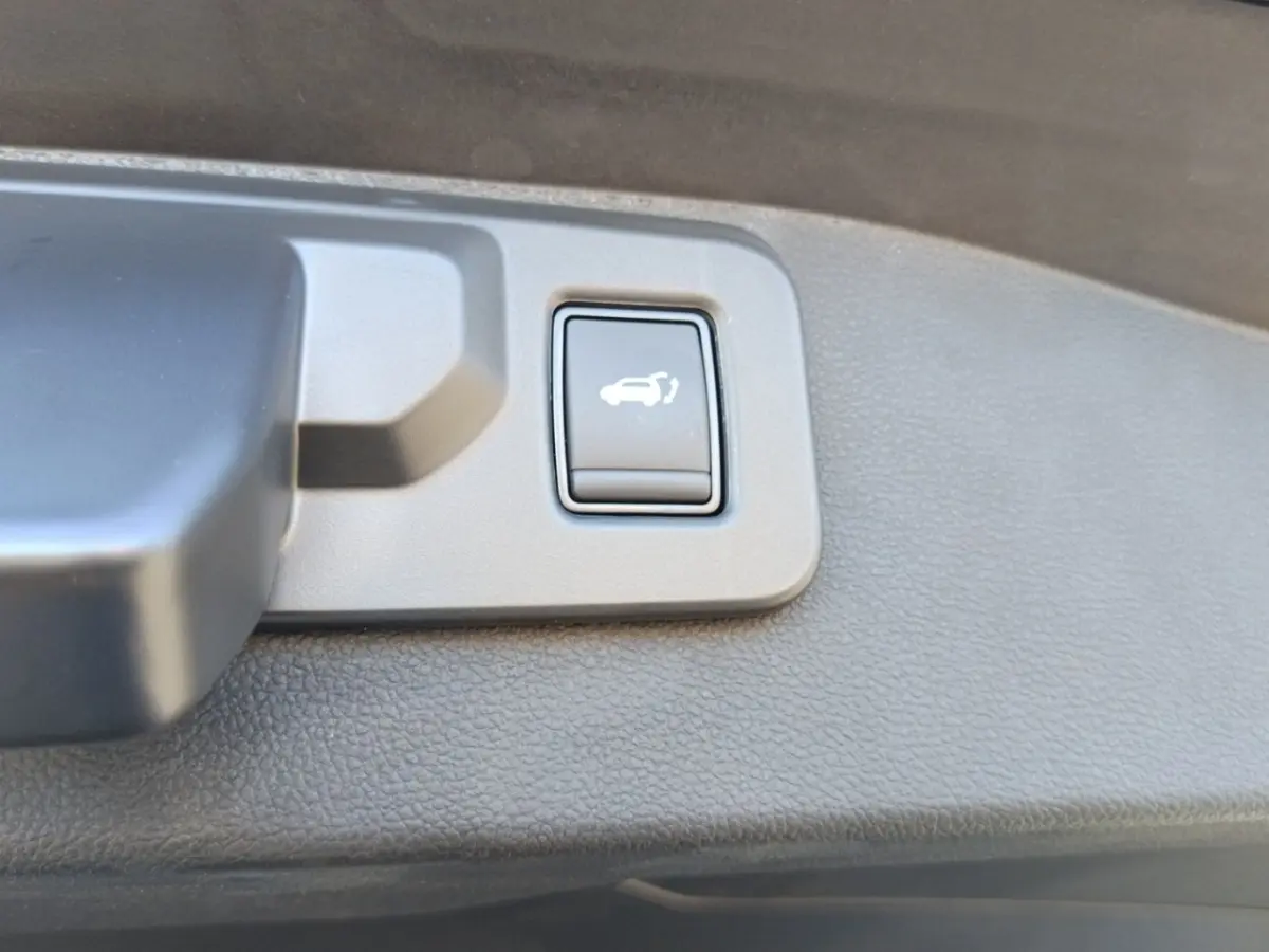 Bouton d'ouverture électrique du coffre sur la garniture intérieure du hayon du Renault Austral blanc esprit Alpine.