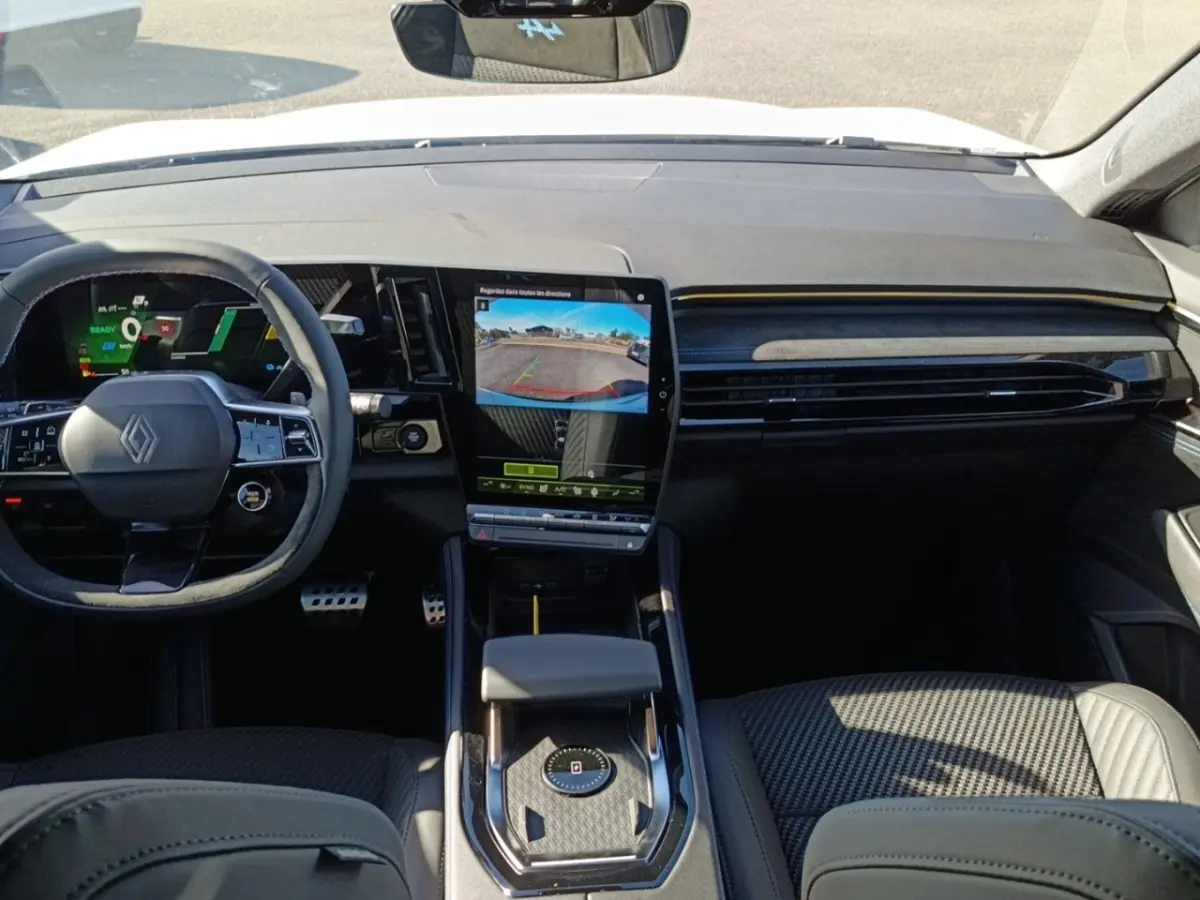 Intérieur de Renault Austral Esprit Alpine, vue avant centrée sur tableau de bord et écran tactile vertical affichant caméra de recul.