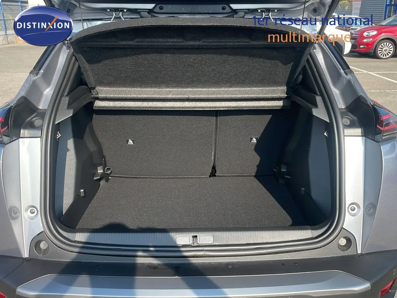 Coffre ouvert vu de l'arrière d'un Peugeot 2008 gris Artense Metal, montrant l'espace de chargement vide.