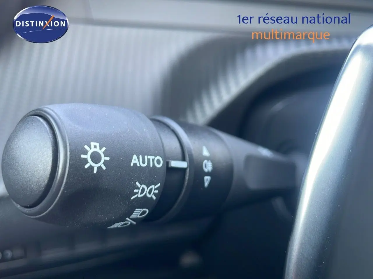 Gros plan sur la commande des phares à gauche du volant dans l'habitacle du Peugeot 2008 gris Artense 2025.