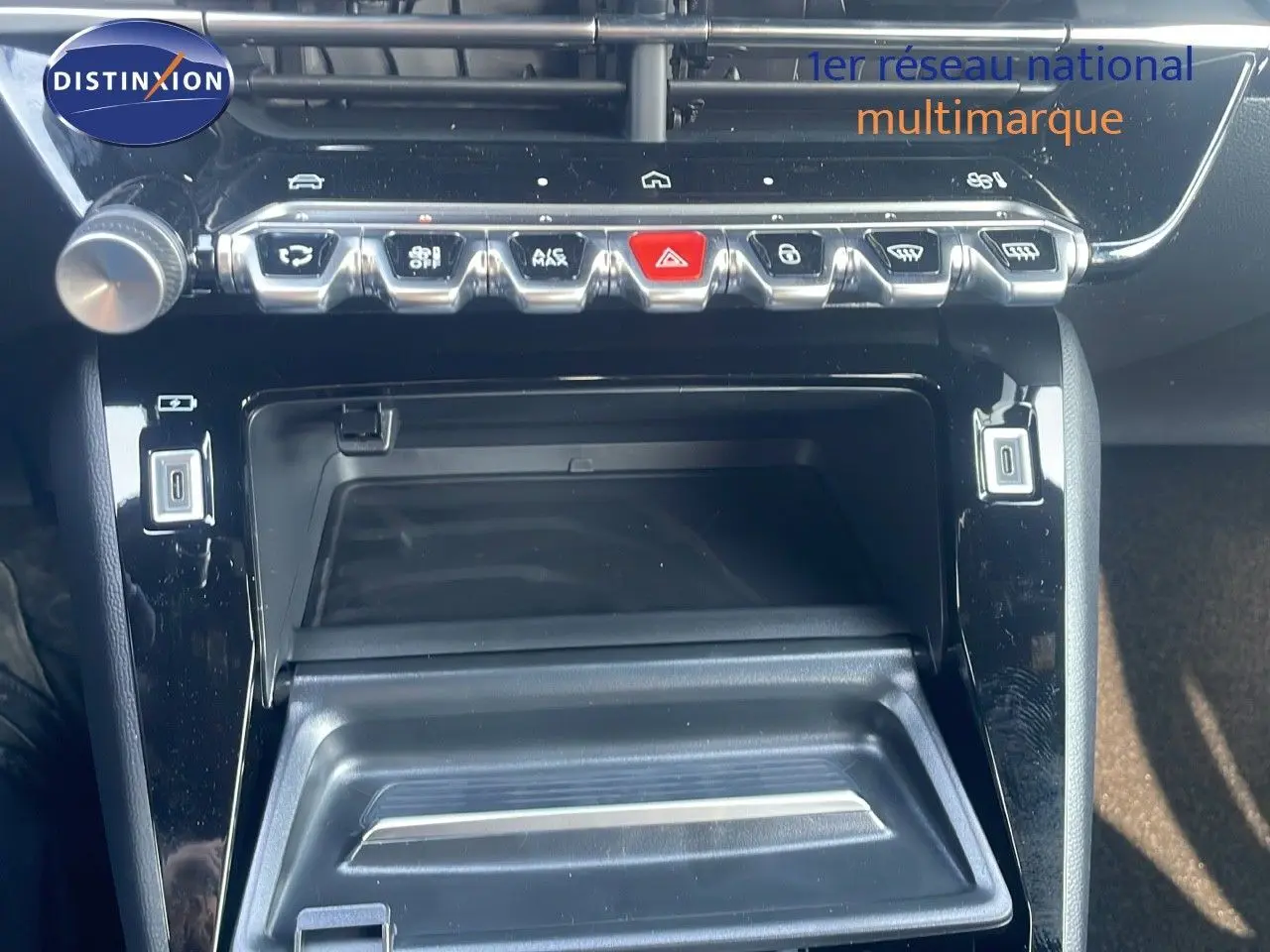 Gros plan sur la console centrale noire brillante du Peugeot 2008 Hybrid 136ch Allure, avec rangements et commandes.