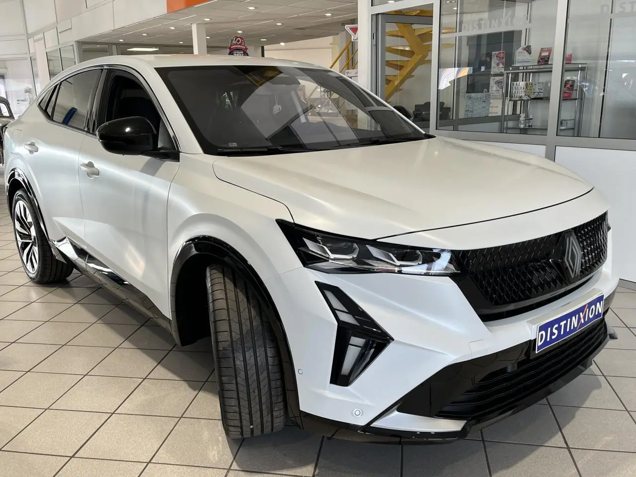 Vue 3/4 avant droite du Renault Rafale blanc 2025 avec calandre noire et jantes alliage noires diamantées.