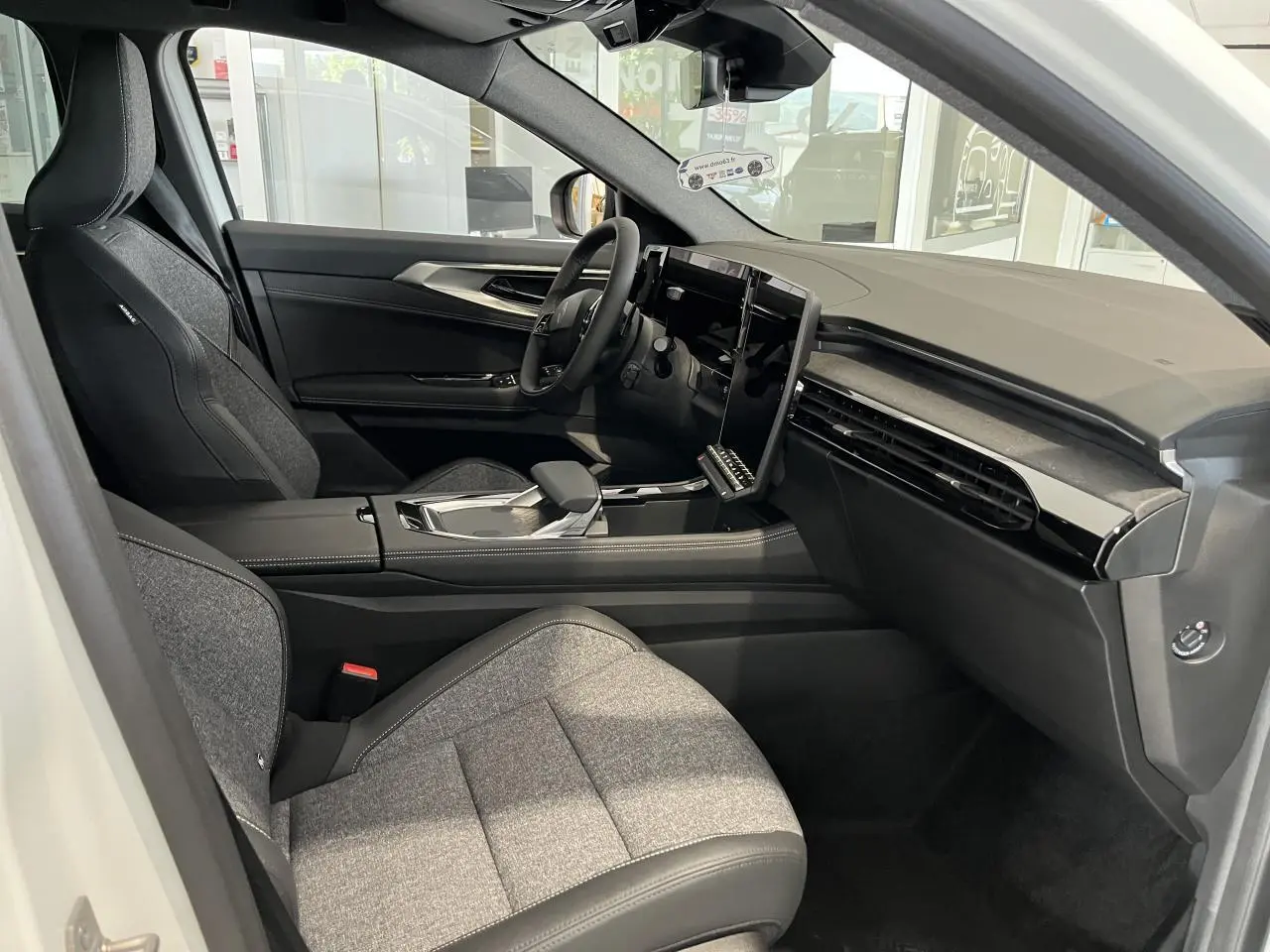 Intérieur de la Renault Rafale 2025 blanc, vue côté conducteur, sièges sport gris textile et tableau de bord moderne.