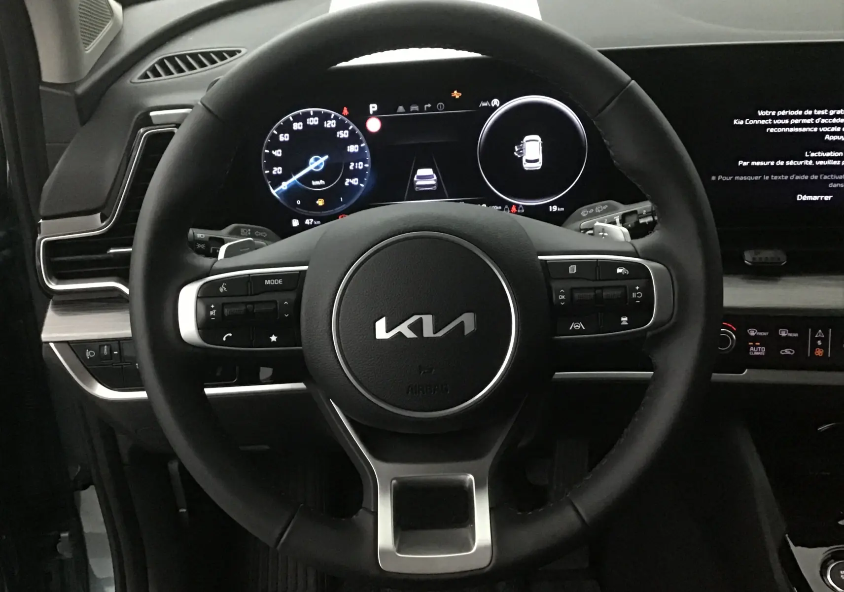 Vue rapprochée du volant noir du Kia Sportage 2025 avec combiné digital et écran tactile à droite.