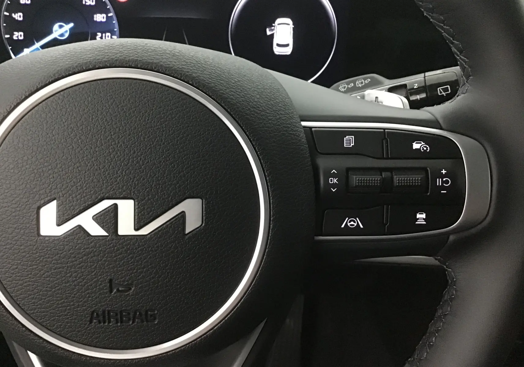 Vue rapprochée du volant cuir noir du KIA SPORTAGE 2025 avec commandes intégrées et logo KIA central gris Sirius.