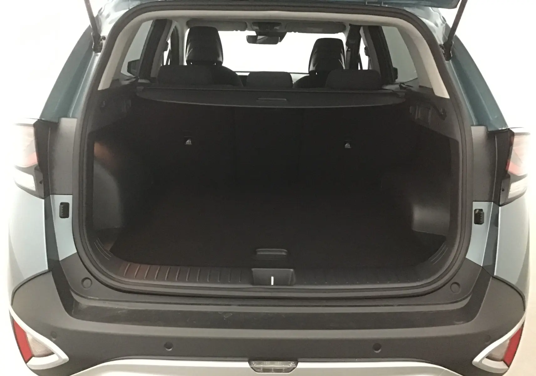 Coffre ouvert vu de l'arrière d'un KIA SPORTAGE gris Sirius 2025, montrant l'espace de chargement et les sièges arrière.