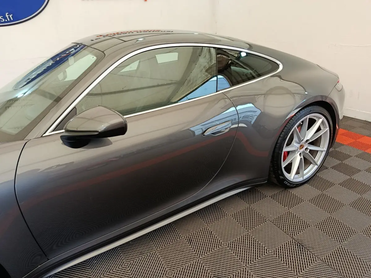 Vue de profil côté gauche d'une Porsche 911 Carrera 4S Coupé gris foncé avec jantes sport et étriers rouges.