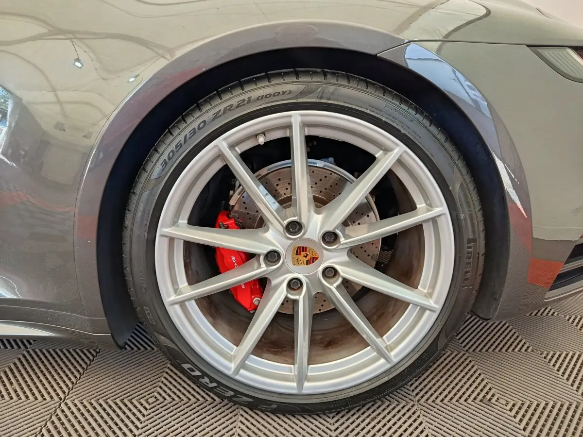 Gros plan sur la roue avant droite grise d'une Porsche 911 Carrera 4S avec étrier de frein rouge visible.