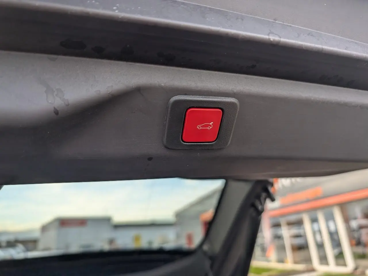 Bouton rouge d'ouverture électrique du hayon visible depuis l'intérieur arrière du Peugeot 3008 blanc 2025.