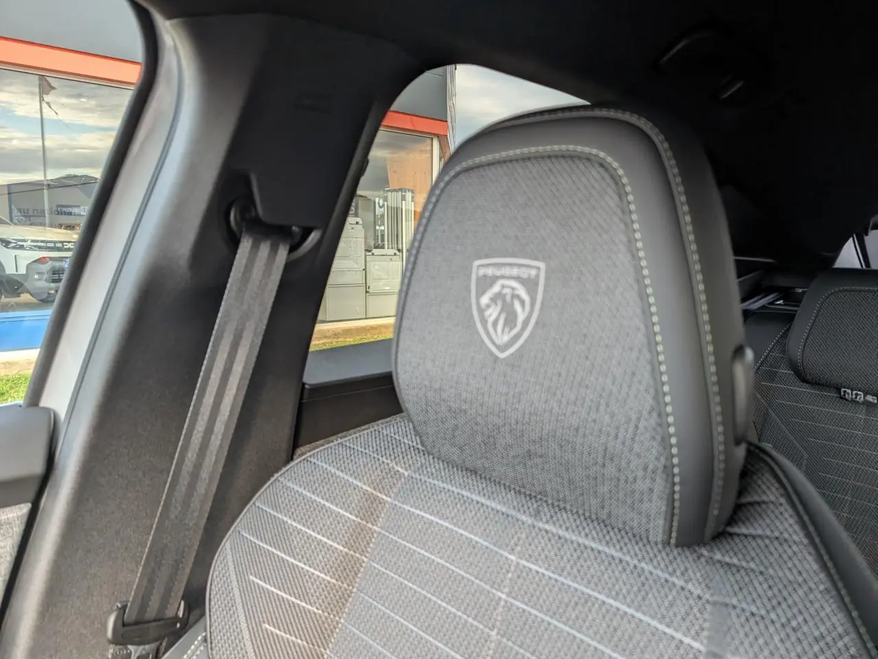 Détail du siège avant gris avec logo Peugeot embossé, vue intérieure côté gauche du Peugeot 3008 blanc 2025.