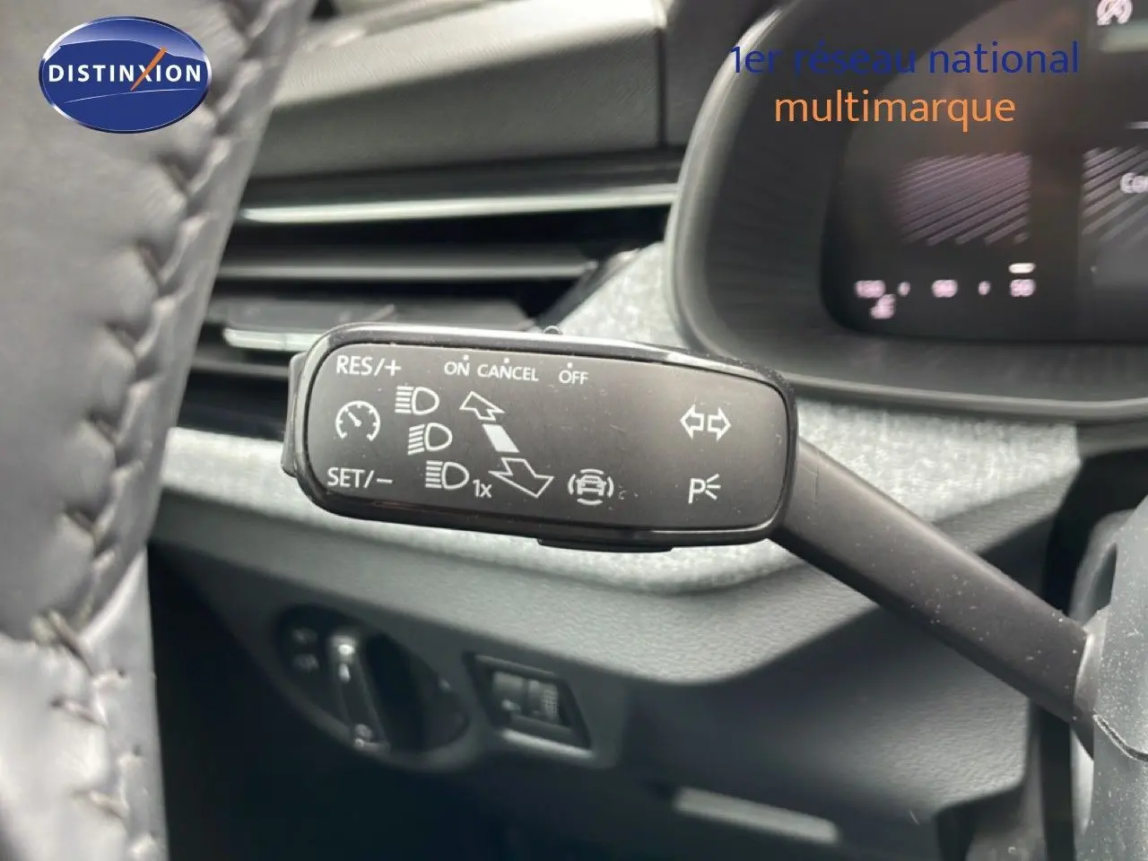 Gros plan sur la commande de régulateur de vitesse à gauche du volant dans l’habitacle gris noir d’une Skoda Scala noir magique métal.