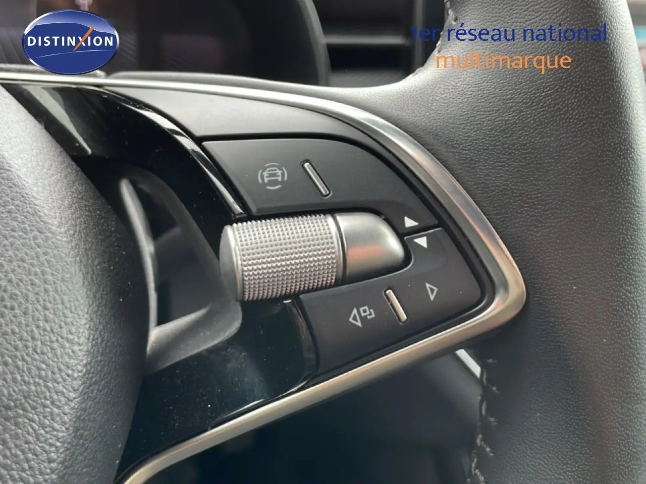 Gros plan sur les commandes au volant d'une Skoda Scala 2025, finition noire avec détails chromés et molette texturée.
