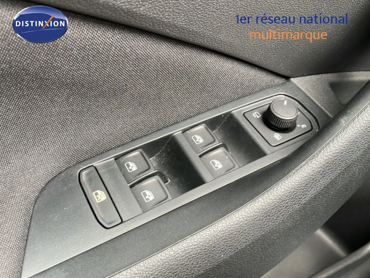 Gros plan sur les commandes des vitres électriques et réglage des rétroviseurs côté conducteur d’une Skoda Scala noir magique métal.
