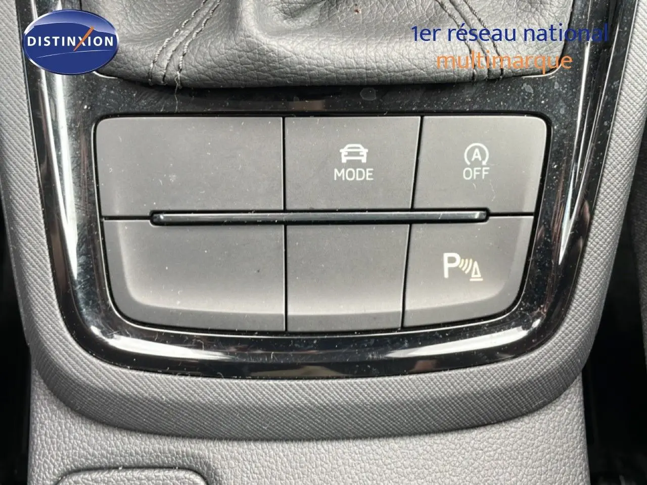 Vue rapprochée du tableau de commandes centrales de la Skoda Scala noire, mettant en valeur les boutons de mode et assistance au stationnement.