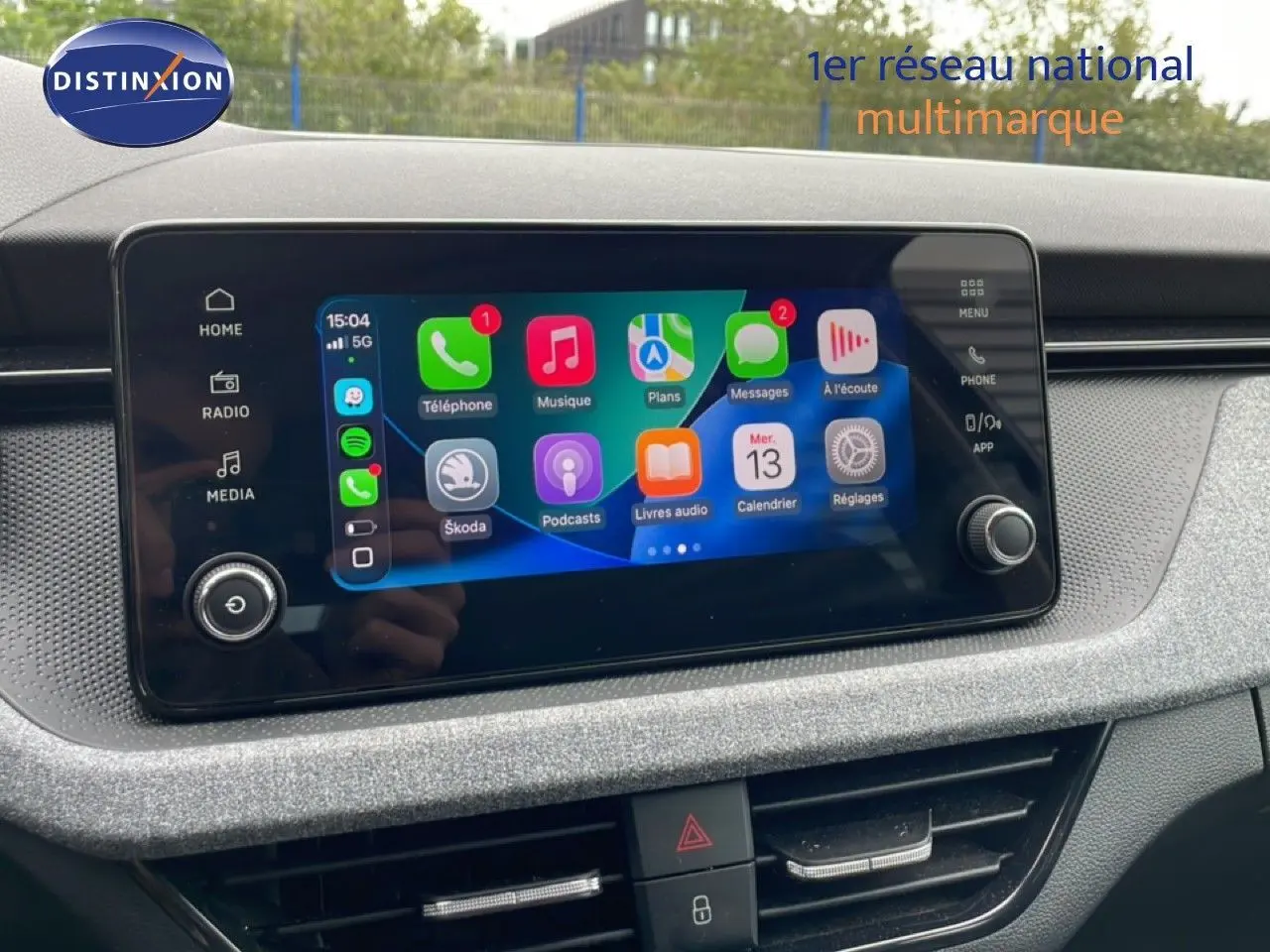 Écran tactile central de la Skoda Scala 2025 affichant Apple CarPlay, entouré d'une console grise texturée.