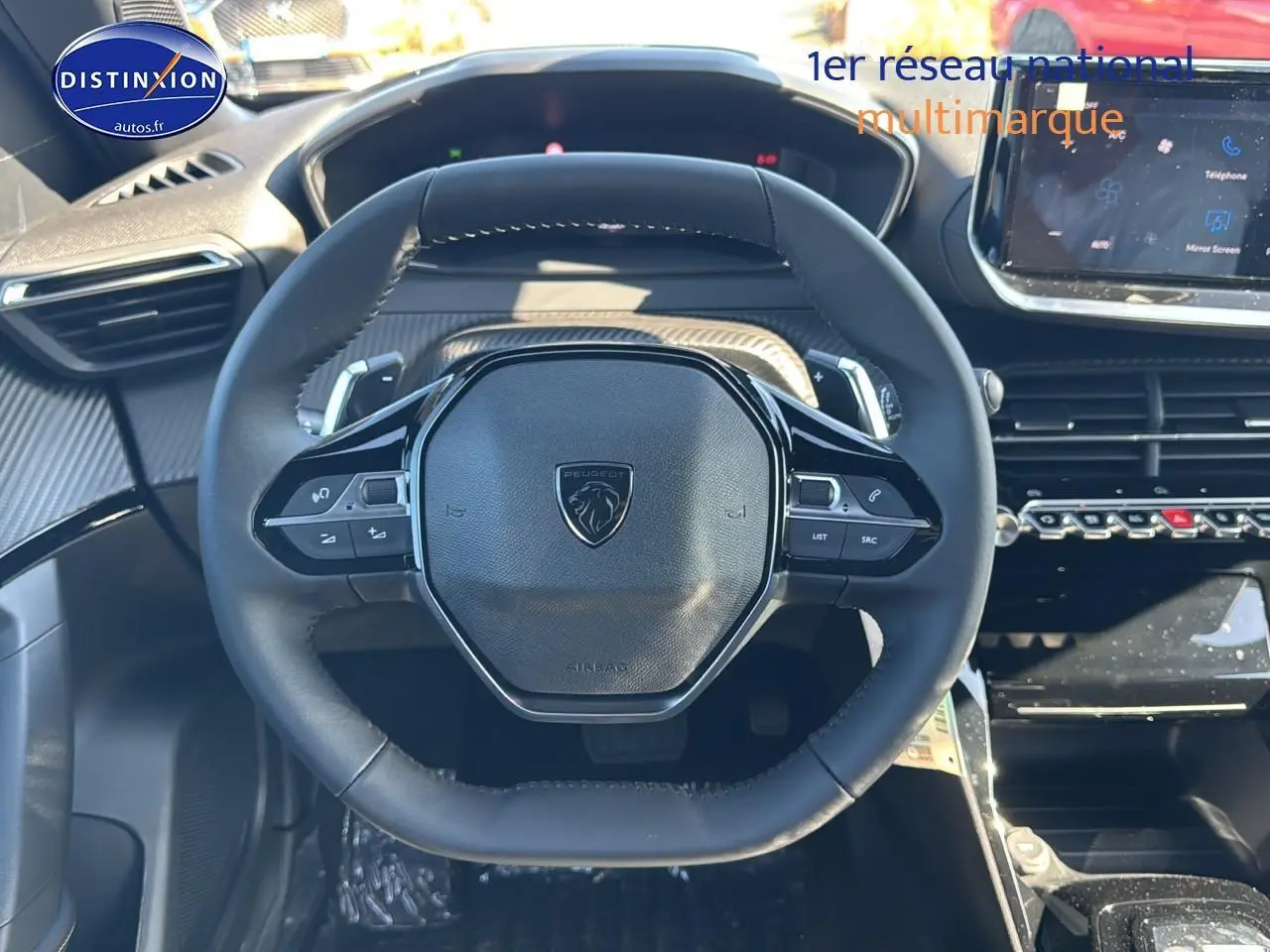 Vue rapprochée du volant noir de la Peugeot 2008 1.2 hybrid 145 allure avec commandes multifonctions et tableau de bord moderne.