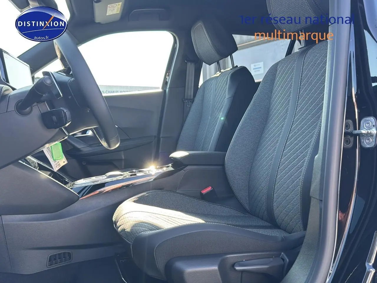 Intérieur de la Peugeot 2008 noir, vue côté conducteur montrant les sièges tissu gris et le volant multifonction.