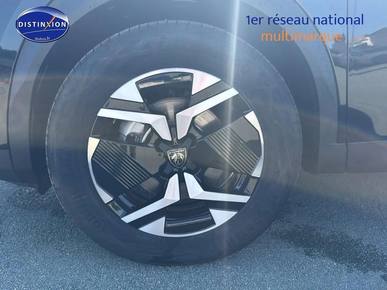 Gros plan sur la roue avant gauche noire avec jante alu au design moderne du Peugeot 2008 1.2 hybrid 145 allure 2025.