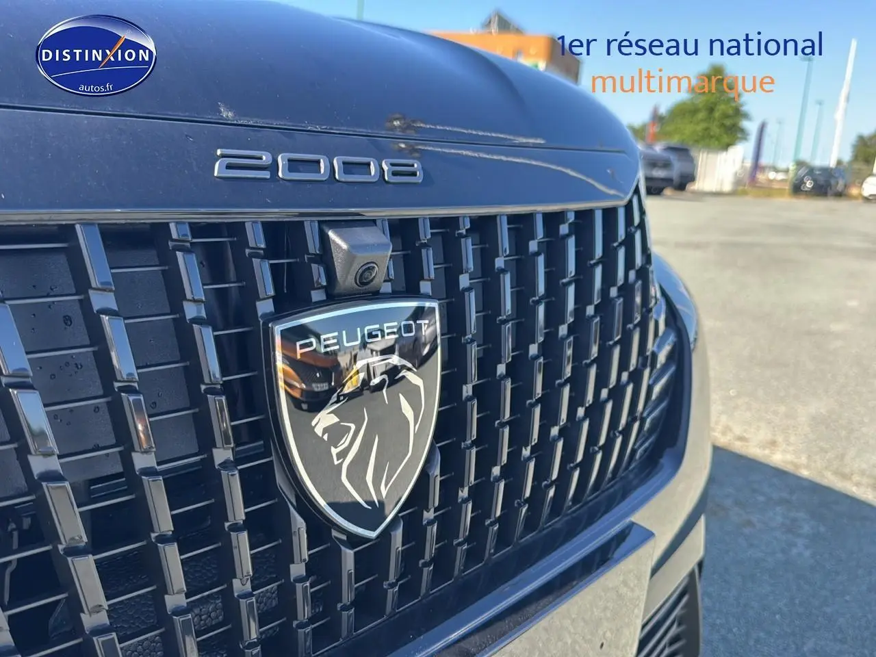 Gros plan sur la calandre noire du Peugeot 2008 2025 avec logo lion et caméra frontale intégrée.