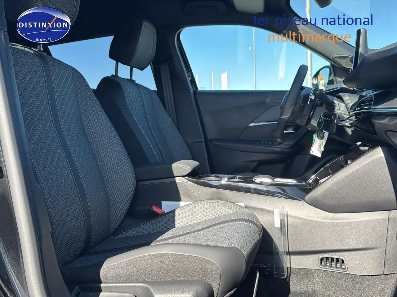 Intérieur de la Peugeot 2008 1.2 hybrid 145 allure 2025, vue côté conducteur, sièges tissu gris et tableau de bord moderne.