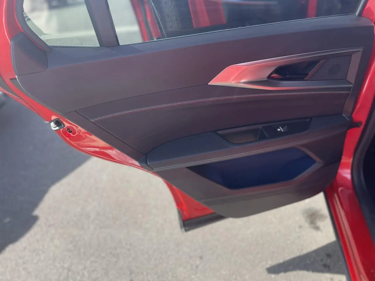 Gros plan sur la porte arrière gauche rouge du Renault Rafale 2025 avec garniture noire et surpiqûres blanches.