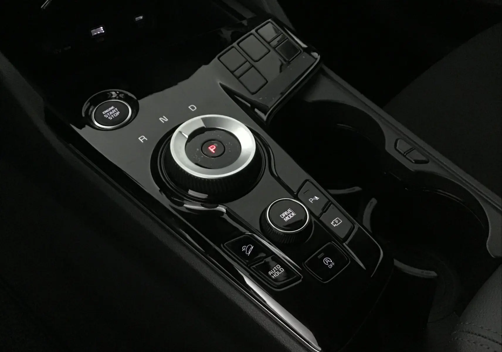 Vue rapprochée de la console centrale noire du Kia Sportage 2025 avec molette de boîte auto et bouton start/stop.