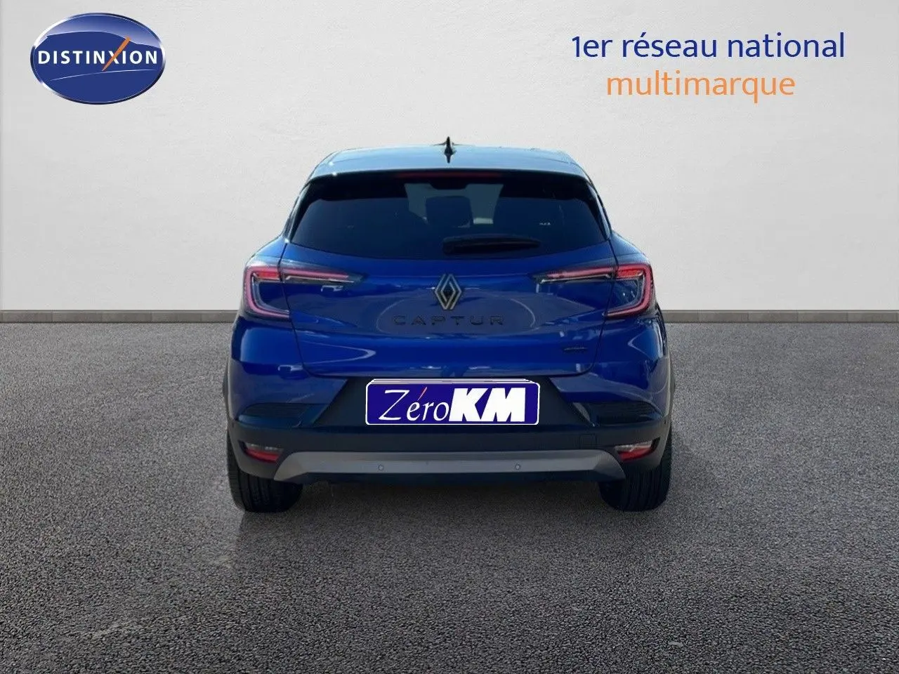 Vue arrière du Renault Captur E-Tech hybride bleu Iron Metal avec toit noir, immatriculé Zero KM, sur sol gris.