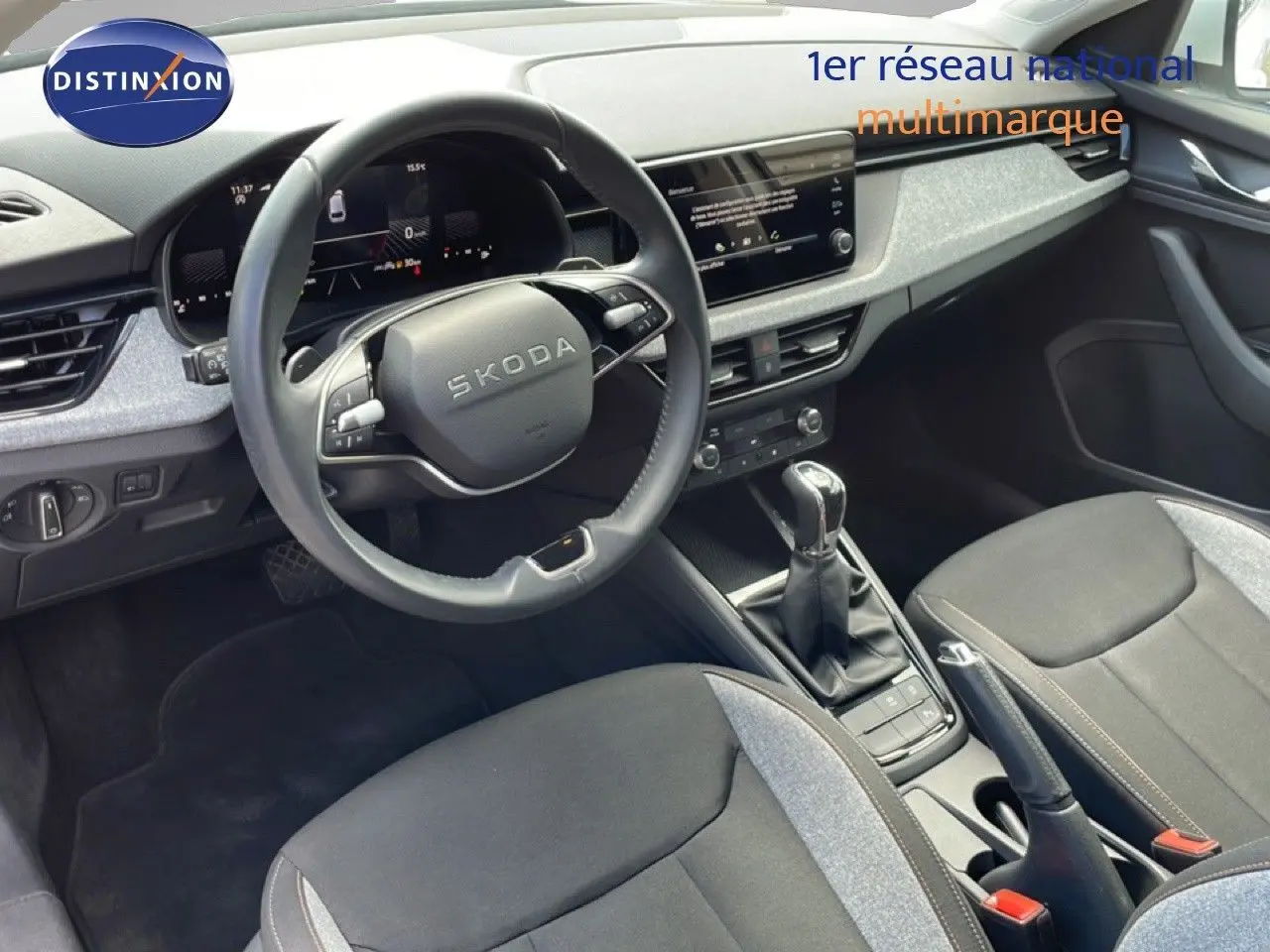 Vue intérieure de la Skoda Scala blanc glacier, montrant le volant multifonction et la console centrale avec boîte automatique.