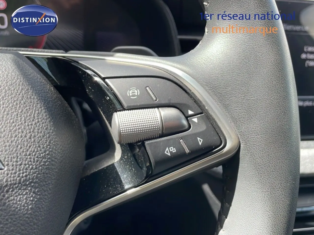 Gros plan sur les commandes multifonctions côté gauche du volant gris d'une Skoda Scala blanc glacier 2025.