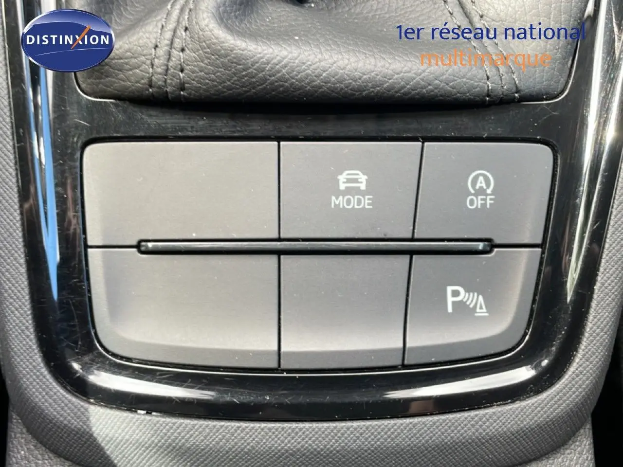 Gros plan sur les boutons de commande de mode et assistance au stationnement dans une Skoda Scala blanche Glacier, intérieur noir.