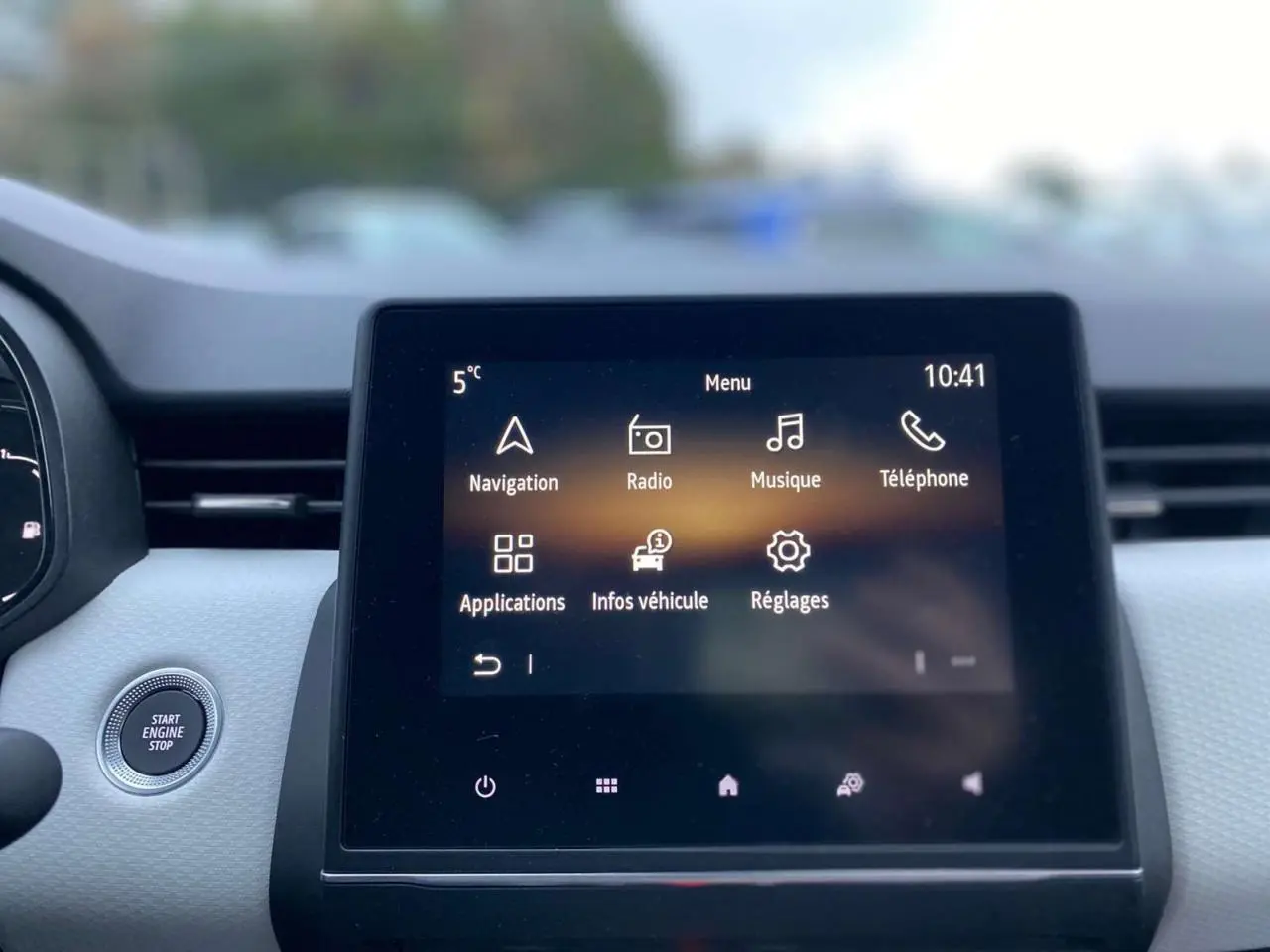 Écran tactile multimédia 7 pouces affichant le menu principal dans l'habitacle clair d'une Renault Clio blanche.