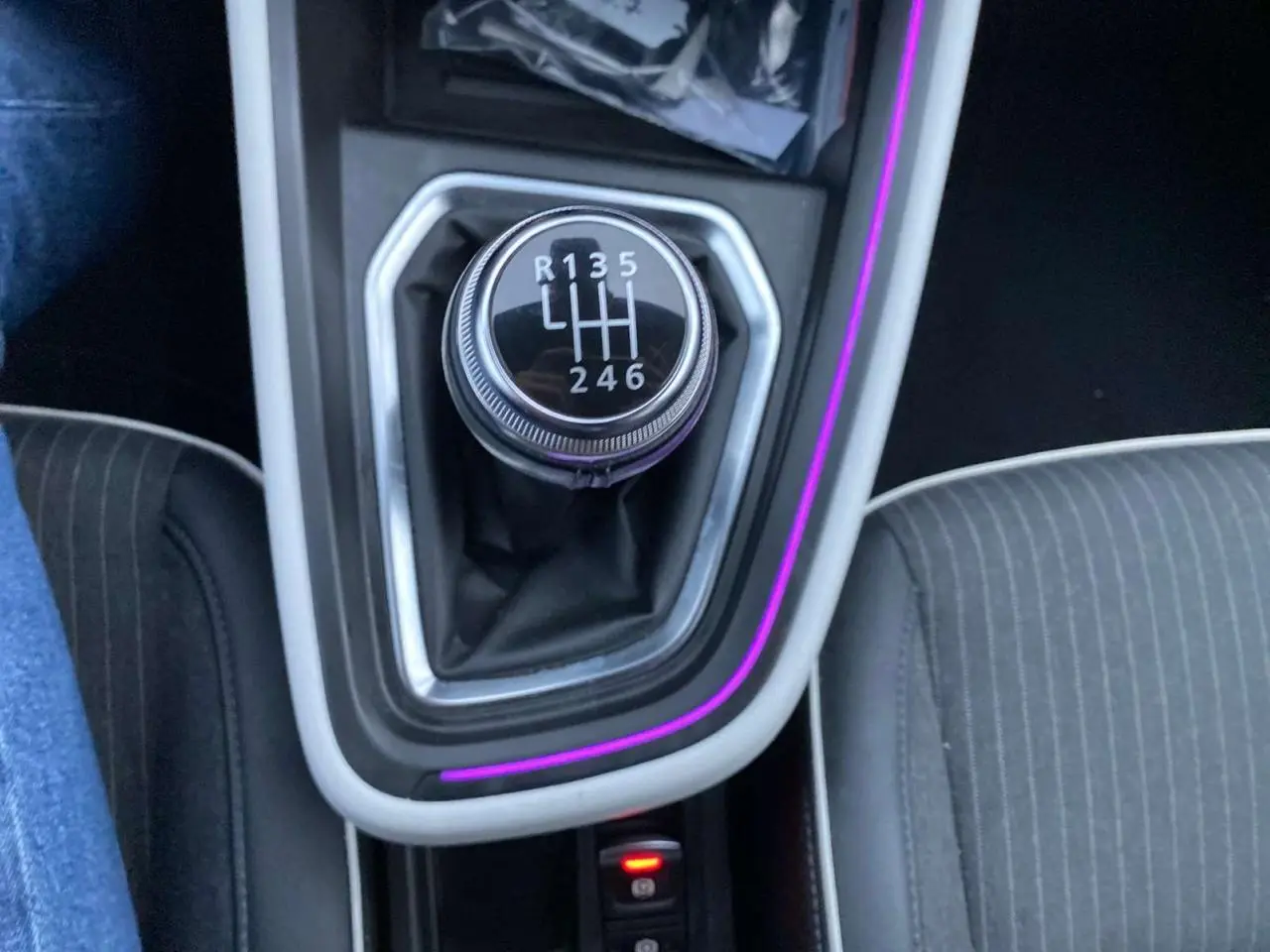 Le levier de vitesses manuel noir de la Renault Clio 2023 avec éclairage d'ambiance violet autour du console central.