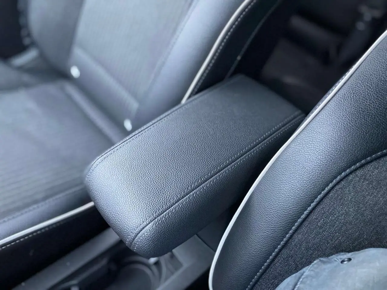 Accoudoir central en similicuir noir et tissu gris sur siège avant d'une Renault Clio 2023.