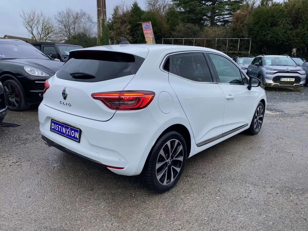 Renault Clio blanc Glacier vue 3/4 arrière droit, avec jantes alliage noires et vitres surteintées.