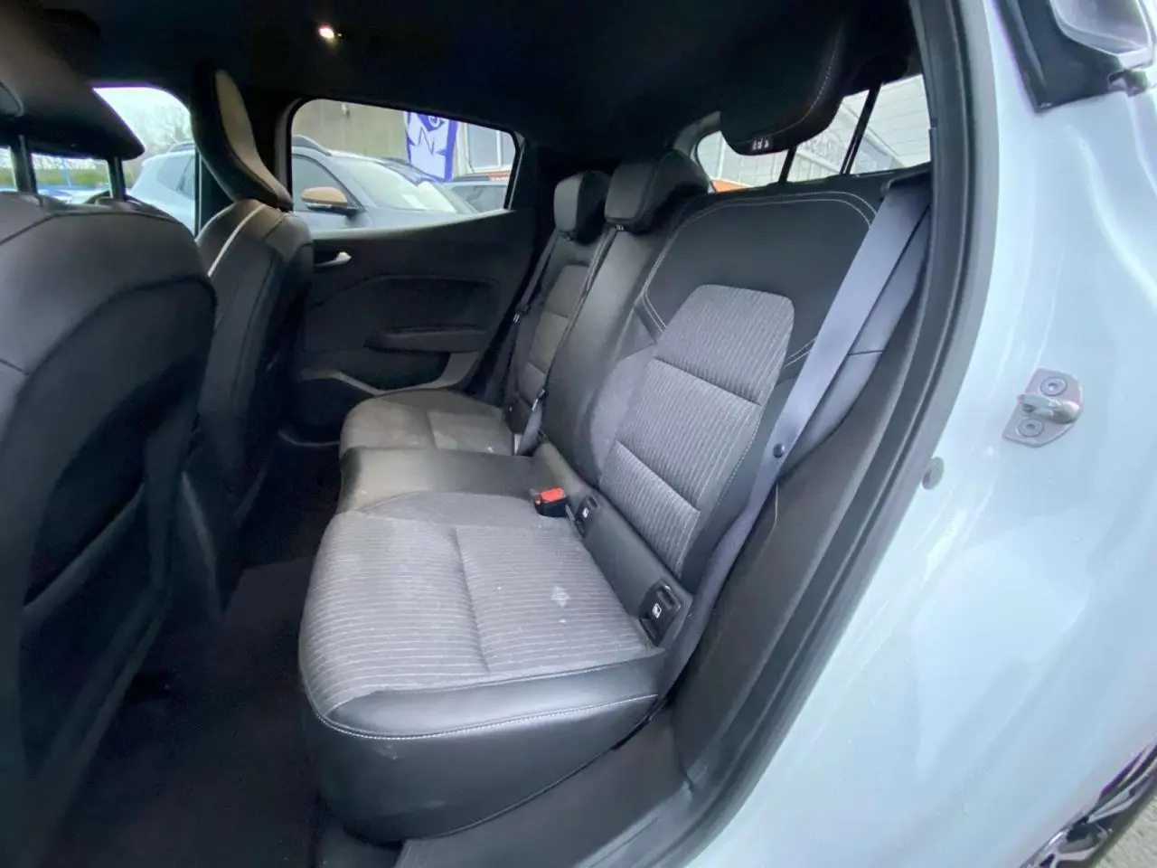 Vue intérieure côté droit montrant la banquette arrière en similicuir tissu gris d'une Renault Clio blanche 2023.