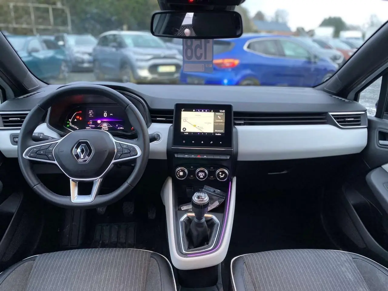 Intérieur de Renault Clio 2023 vu de face, tableau de bord moderne avec écran tactile et levier de vitesse manuel.